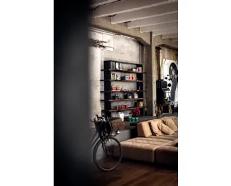 Libreria Crazy realizzata in legno massello caratterizzata da una sottile cornice in ferro e mensole con bordi anteriori naturali che si intersecano e fuoriescono dalla struttura di Riva1920